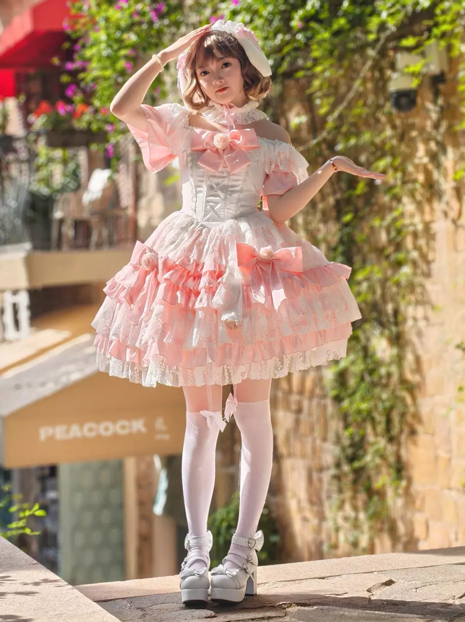 Pink white lolita dress front view with lace bonnet hair accessory white stockings commercial street background