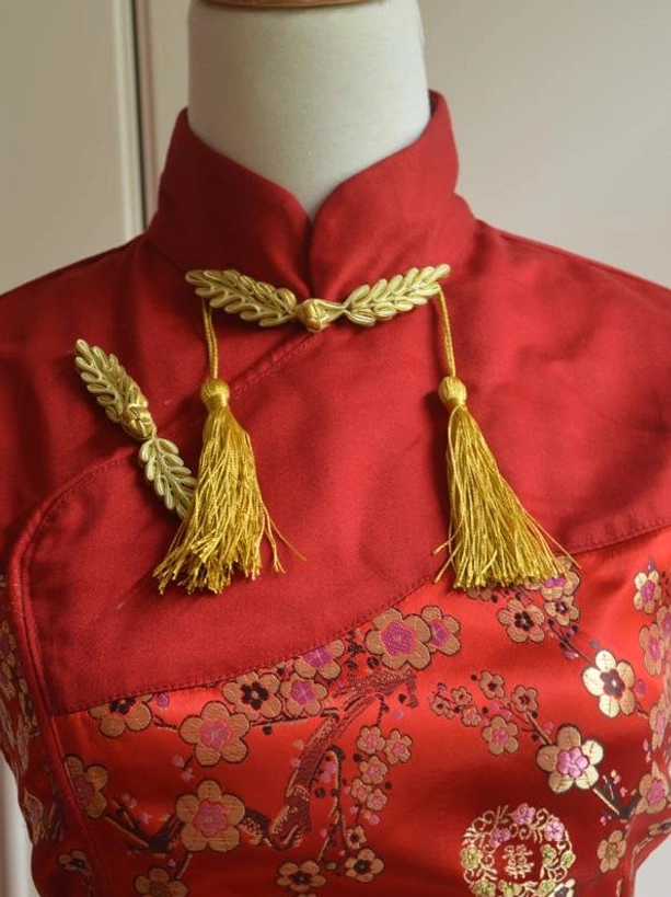 Close-up detail of mandarin stand collar and upper bodice with golden wheat-style clasp tassels and plum blossom jacquard fabric
