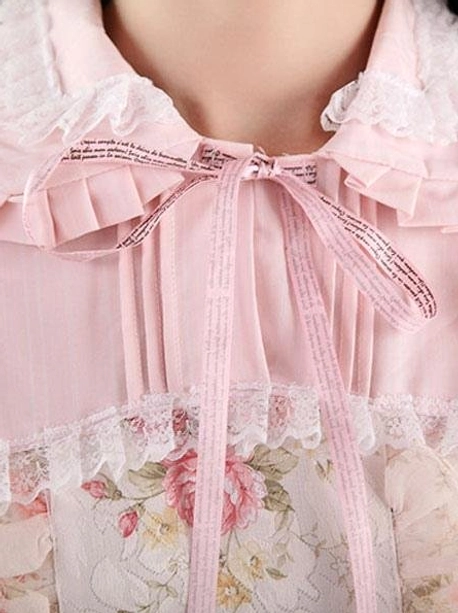 Close-up detail of lolita dress neckline featuring ruffled Peter Pan collar with lace trim, text-printed ribbon bow accent, delicate floral fabric panel, decorative embellishments