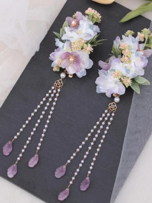 Lolita floral hair clip accessories showing alternate flower arrangement with square hollow metal connectors, lavender and purple-blue blooms, beaded tassel details on elegant black slate with tulle background