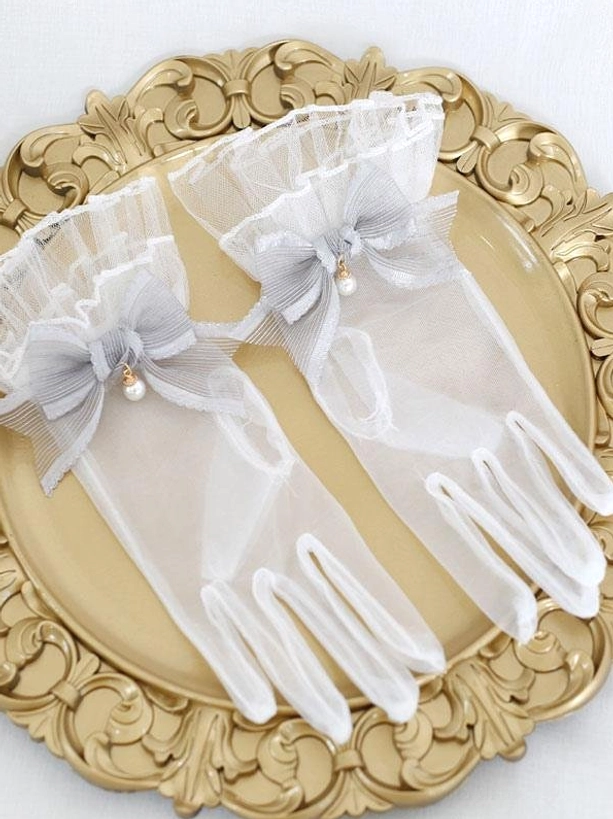 Soft gray pearl bow sheer lolita gloves with ruffled cuffs elegant flat lay on decorative gold tray