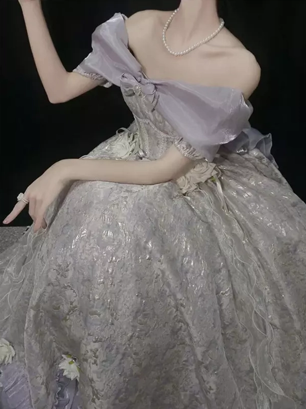 Close-up side view of lolita gown bodice and skirt detail showing lavender off-shoulder bow, pearl necklace accessory, and intricate dimensional floral jacquard texture
