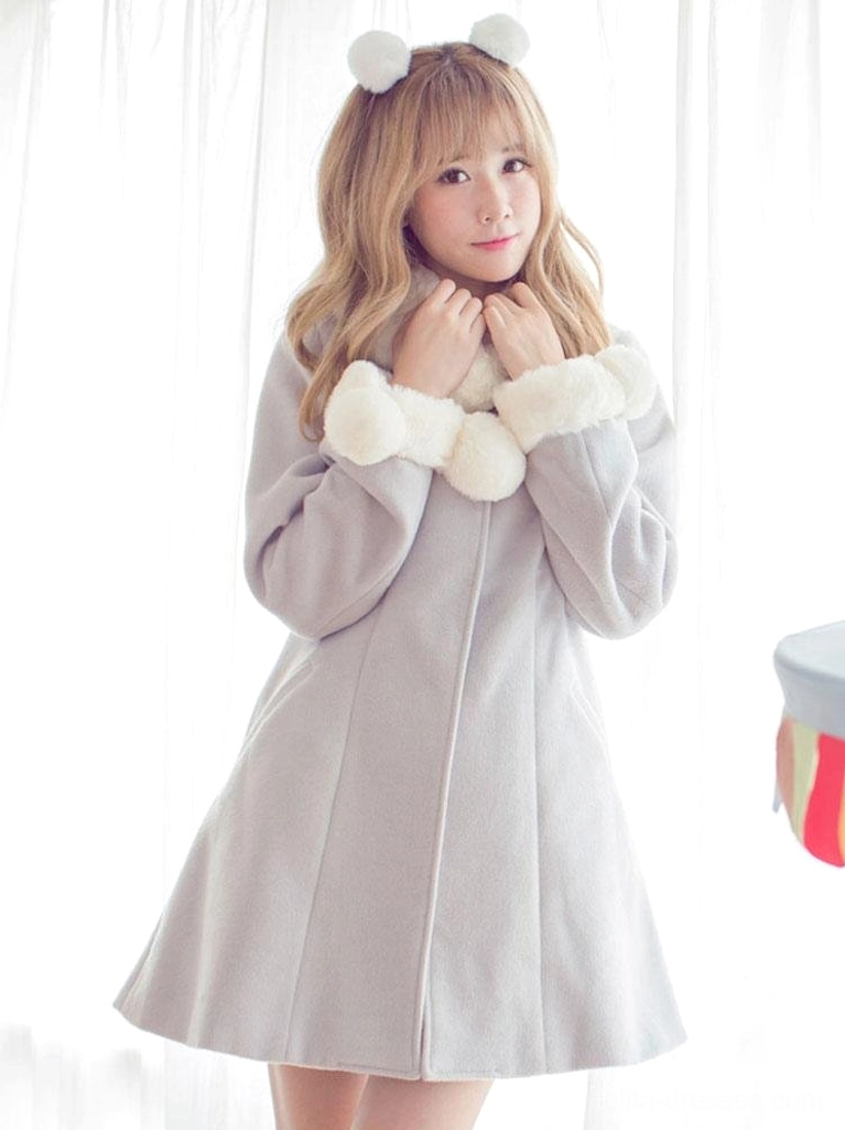 Front full-body shot of grey wool lolita coat highlighting the wide fuzzy wrist trims, decorative pom pom collar design, and flared hemline that creates the signature lolita silhouette, worn by blonde model with pom pom hair accessories