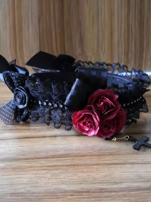 Lolita headdress flat lay product shot displaying full black lace band checkered bows wine red roses detachable cross pendant wooden surface
