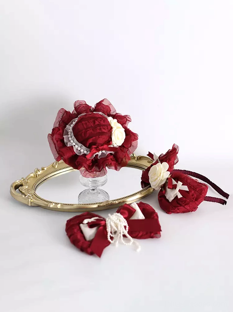 Lolita hair accessory set flat lay featuring wine red bow clip with cream flowers and small bow clips displayed on gold-rimmed mirror tray