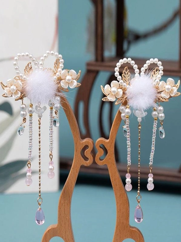 Twin lolita hair accessories with gold finish, white fluffy pom-poms, pearl and floral accents, extended beaded tassels on dual wooden display stand