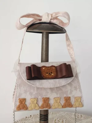 Cute Lolita handbag displayed on stand showcasing satin bow shoulder strap, brown teddy bear decoration, ruffled design, and detailed bear trim embellishments