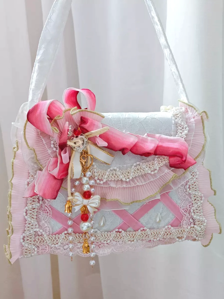 Lolita fabric strap handbag flat front side view with gradient pink ribbon bow, ruffled lace embellishment, beaded tassel decor, and pink cross webbing design