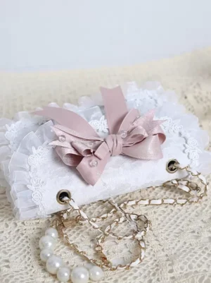 Lolita handbag side angle showing layered pink satin bow with pearl accents and pearl-chain crossbody strap detail