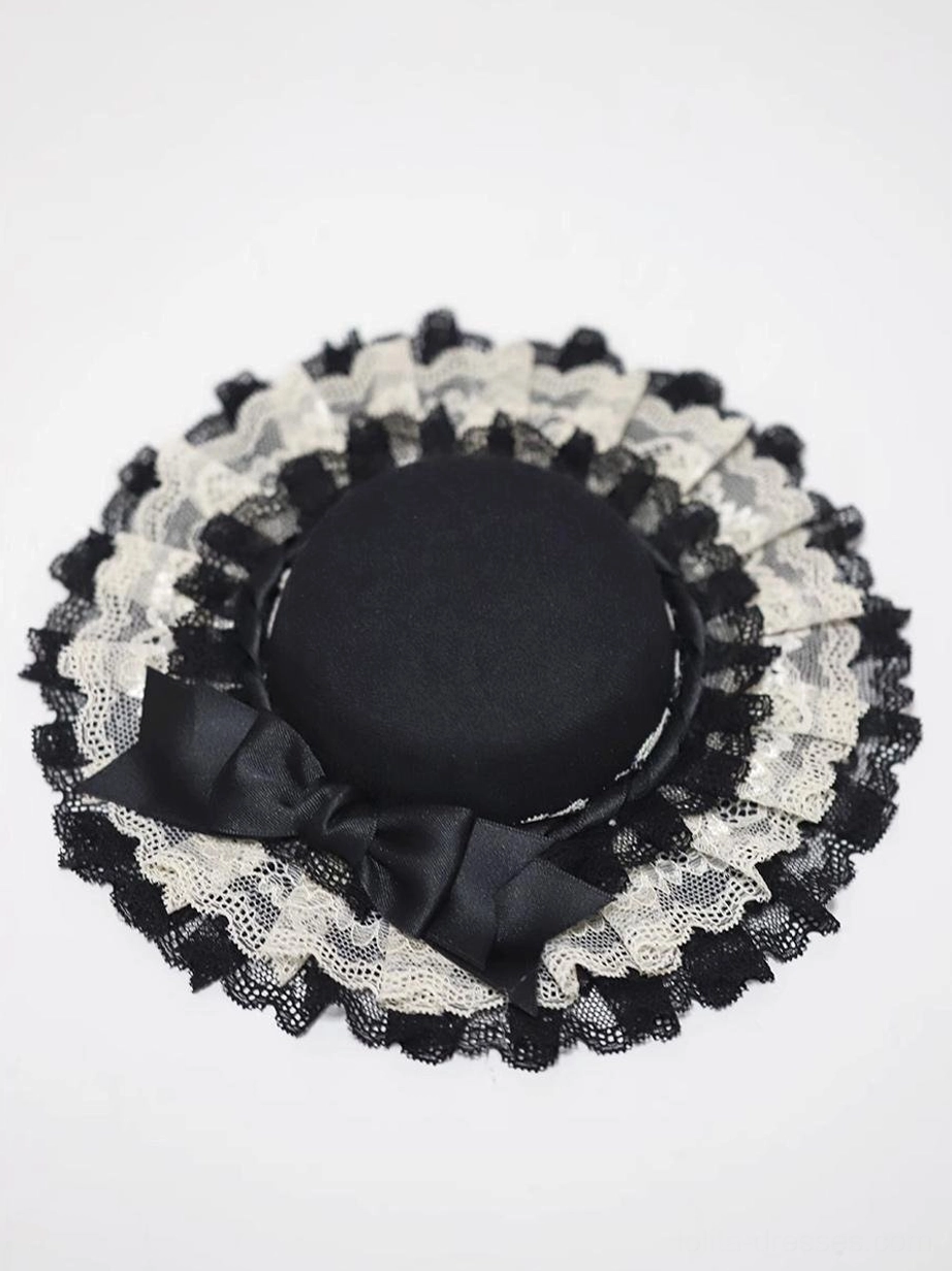 Black crown Classic Lolita mini top hat top-down flat view displaying symmetrical lace trim ruffles and centered black satin bow on white background