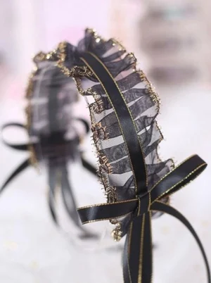 Lolita frilled hair headband with black mesh ruffle and gold trim, featuring black satin bow on wired fabric headband frame, front flat lay display