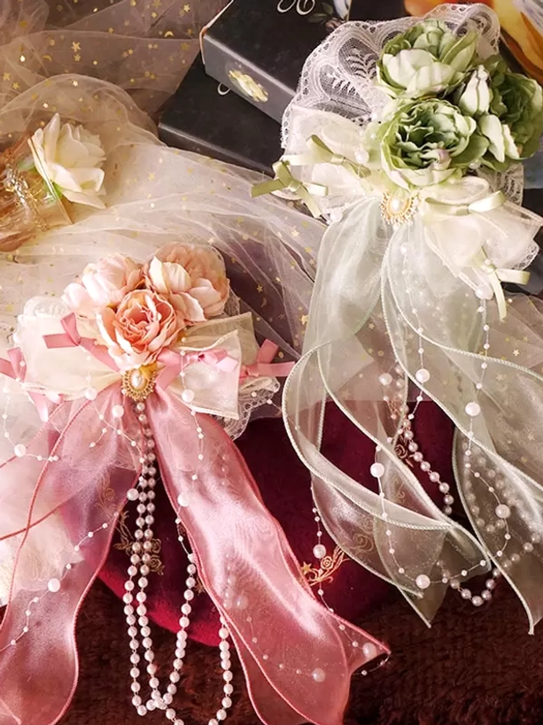 Overhead flat lay composition of two coordinated lolita hair accessories with complementary color variations, featuring pearl-embellished designs, artificial flowers, and ornamental bows arranged on vintage velvet background
