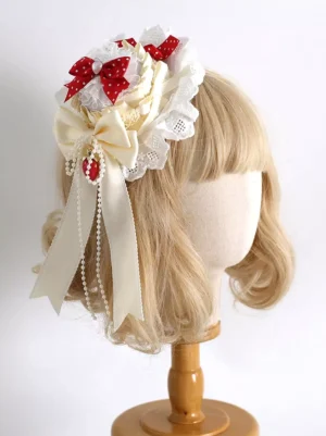 Cream satin bow lolita headdress with strawberry charm and pearl chains worn on blonde mannequin, demonstrating sweet lolita coordinate styling