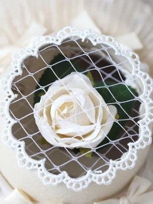 Beige lolita mini top hat overhead top-down shot showing white rose scalloped lace edge and mesh veil detail