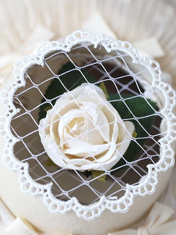 Beige lolita mini top hat overhead top-down shot showing white rose scalloped lace edge and mesh veil detail