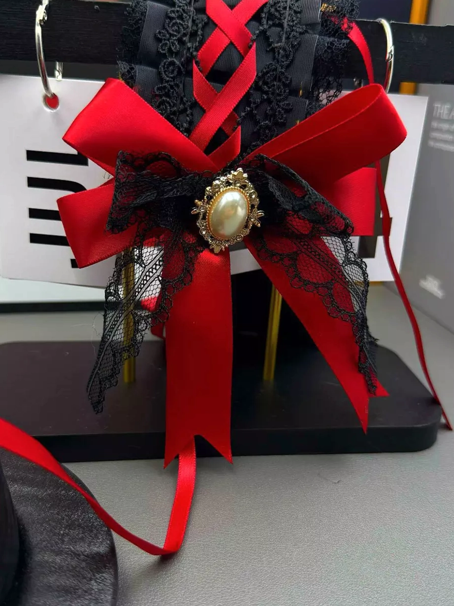 Lolita headdress shown from front view on metal display stand, showcasing the ornate red satin bow, delicate black lace details, and prominent oval pearl brooch centerpiece