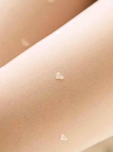 Extreme close-up macro shot of delicate white velvet fabric with tiny heart embroidery dots and sheer texture detail