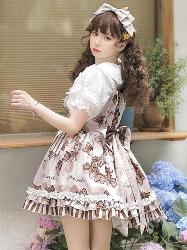 Lolita jumper skirt back three-quarter view displaying back bow decoration, crisscross back straps, ruffled skirt hem on model with twin curly brown hair