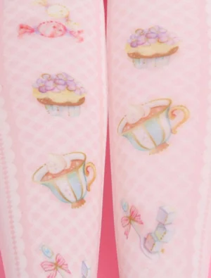 Close-up frontal view of printed lolita knee-high socks showing detailed teacup cupcake and candy motifs in soft pastel colors with scalloped sock top trim on leg