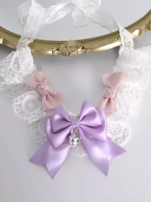 Lavender lace bow choker with heart gem dangling pendant and pink bow decorations styled on vintage gold tray flatlay top-down product photography