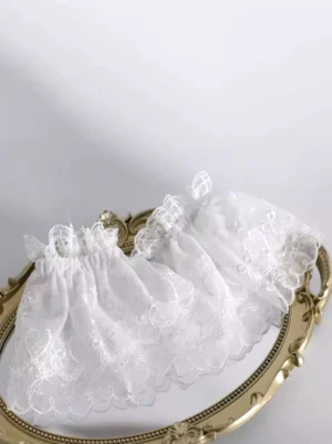 Delicate white embroidered lace fingerless gloves with ruffled elastic cuff displayed on vintage golden tray, showing scalloped lace edges and elegant bow design for sweet lolita coordinate styling