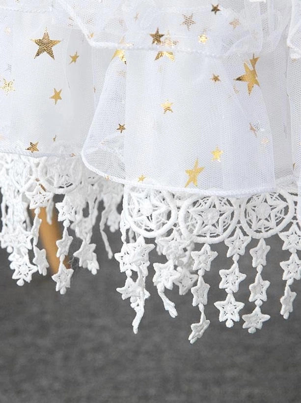 Detailed side view of black star print petticoat hem showing gold stars on mesh fabric and star-shaped lace tassel trim