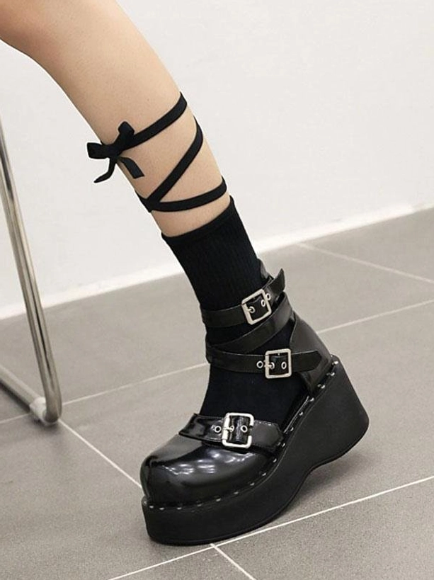 Black patent lolita platform shoes on model leg with bow-tie socks side single foot view highlighting silver buckles round toe and platform sole