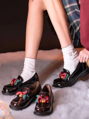 Lolita leather pumps close-up detail of lower legs wearing white ruffled socks and festive bow bell decoration on low block heel chunky base