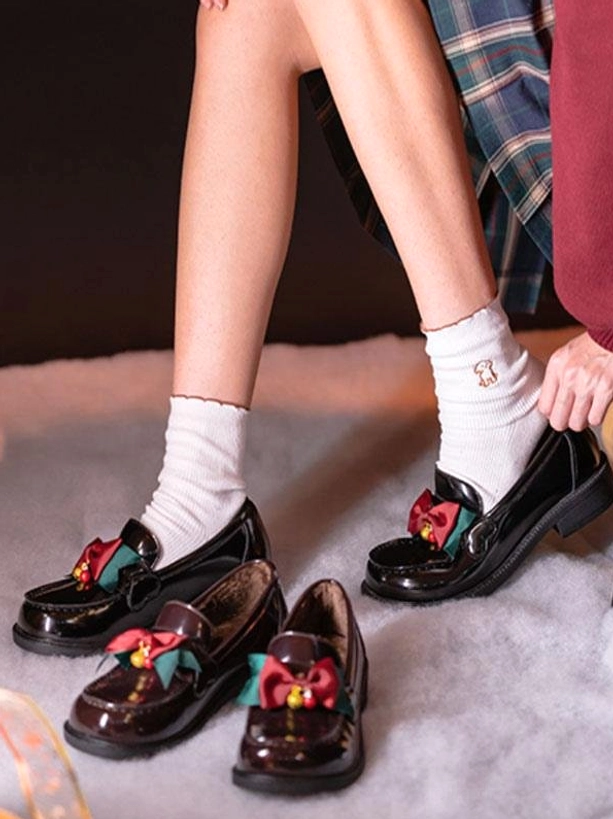 Lolita leather pumps close-up detail of lower legs wearing white ruffled socks and festive bow bell decoration on low block heel chunky base