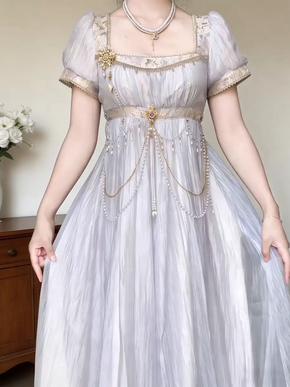 Close-up detail of purple Lolita Regency dress featuring square neckline with trim, decorative gold brooch, layered waist chains, and upper bodice embellishments