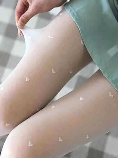 Hand adjusting sheer white heart-patterned Lolita stockings on checkered floor background with green skirt showing stretchy fabric