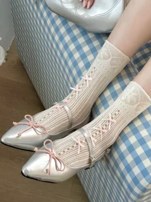 Lolita mid-calf socks featuring light beige color with pink bow straps and delicate lace trim, leg view on blue checkered sofa