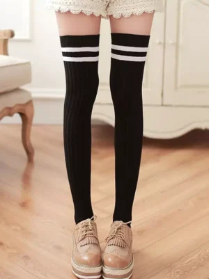 Black and white two-tone stripe over-the-knee lolita socks front view worn with tan loafers full leg styling