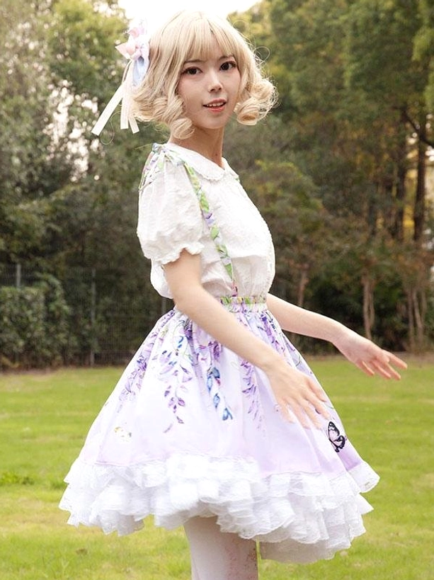 Green suspender straps and three-quarter side view of lilac lolita skirt showing ruffled underskirt construction and a-line silhouette on model in outdoor setting