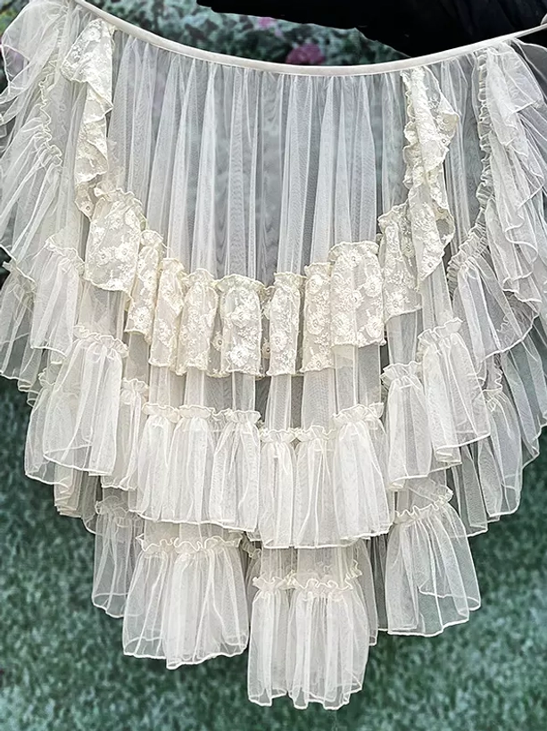Lolita tulle sweep train overlay with lace appliqué trim and multi-layer ruffled construction shown in flat lay overhead view