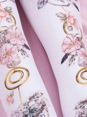 Close-up side leg view of pink lolita tights showing delicate pink flowers gold circular hardware pocket watch and key motifs on model