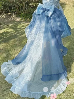 Detachable blue organza Lolita train accessory with ruffled hem and floral bow ornament low angle rear view grassland setting