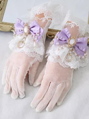 Light pink velvet Lolita wrist gloves with purple satin bows, white ruffled lace, and pearl heart charms - overhead flat lay styling