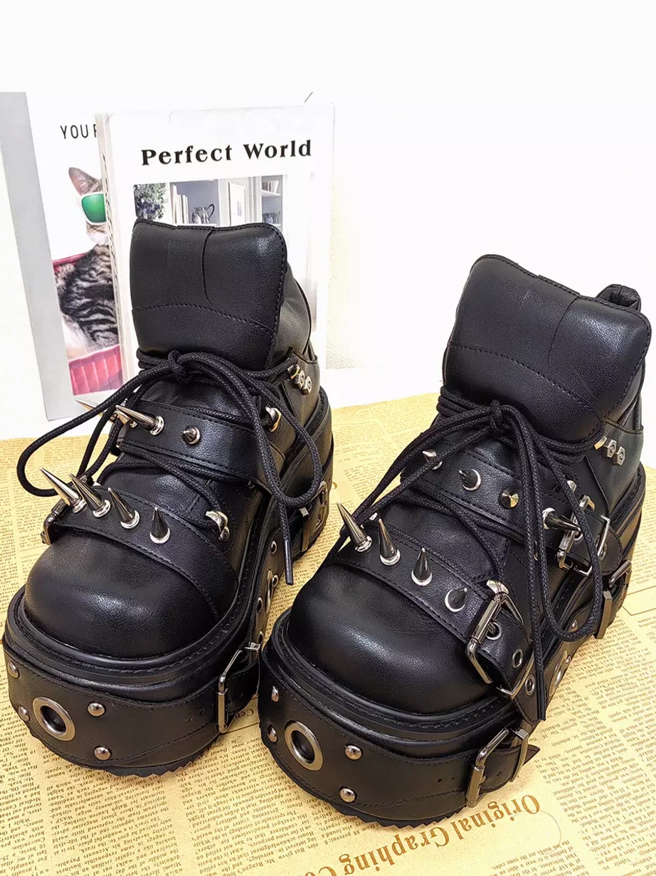Gothic Lolita boots featuring lace-up closure and thick studded platform sole displayed on newspaper background with decorative books styling