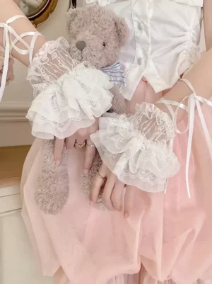 Lolita white lace wrist cuffs with ribbon ties satin bows styled with teddy bear and pink skirt indoor photography
