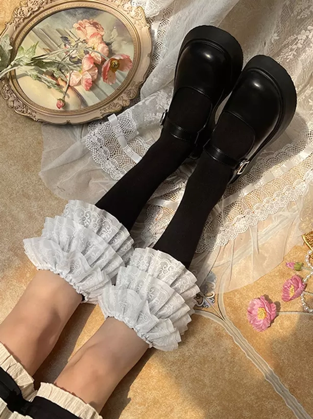 Lolita white ruffled leg cuff accessory with multi-layer lace detail black stockings flat lay styling top-down view