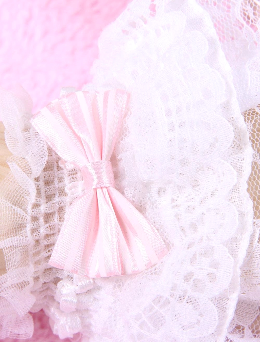 lolita wrist cuff flat lay close-up featuring large pink satin bow scalloped white lace and mesh frills