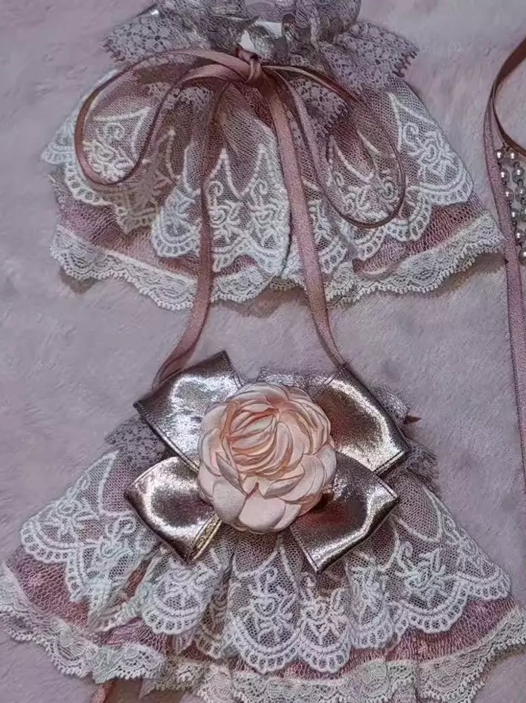 Lolita lace wrist cuffs with scalloped edges, large satin bow, 3D pink rose decoration, and matching satin ribbons flat lay photography