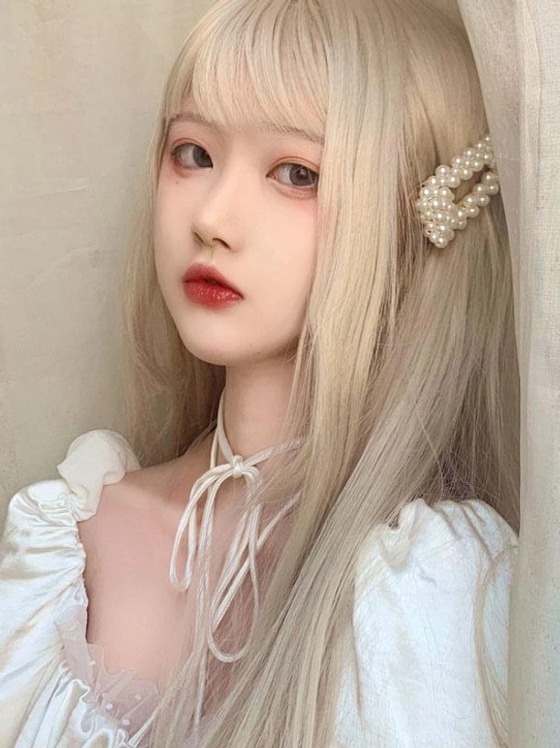 Side three-quarter view of long straight blonde Lolita wig showing blunt bangs silky smooth synthetic fiber texture and pearl hair accessory