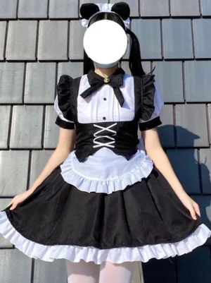 Black gothic maid lolita dress front view showing model in cat ears resting hands on ruffled skirt edge and hem details against traditional Asian tile roof background