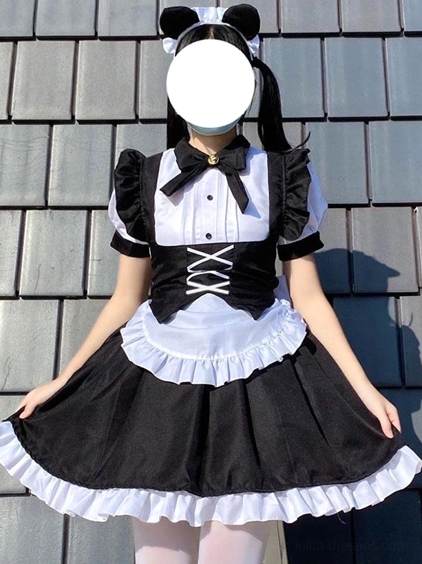 Black gothic maid lolita dress front view showing model in cat ears resting hands on ruffled skirt edge and hem details against traditional Asian tile roof background