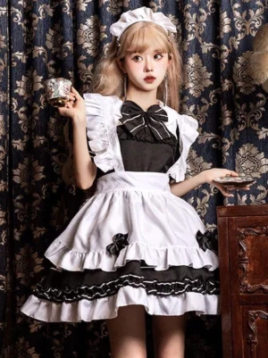 Black maid lolita dress with layered ruffles and bow details - front three-quarter view model holding vintage teacup showcasing costume styling
