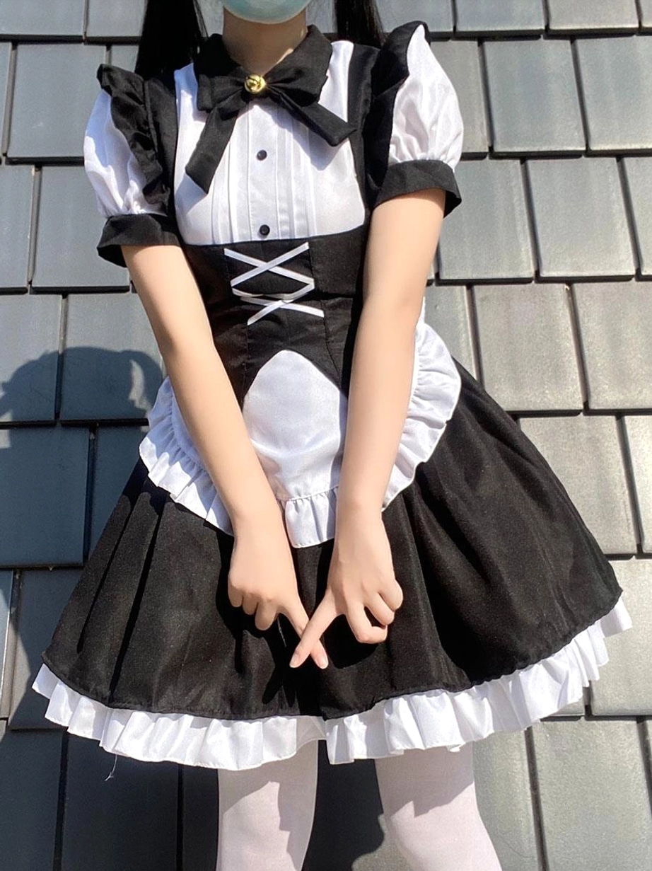 Maid lolita dress front side angle showing model in mask with detailed lace-up corset waist, ruffled apron trim, and black-white gothic color scheme