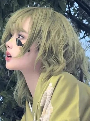 Matcha green short wavy lolita wig with air bangs, left profile close-up view outdoors showing delicate wavy texture and soft framing