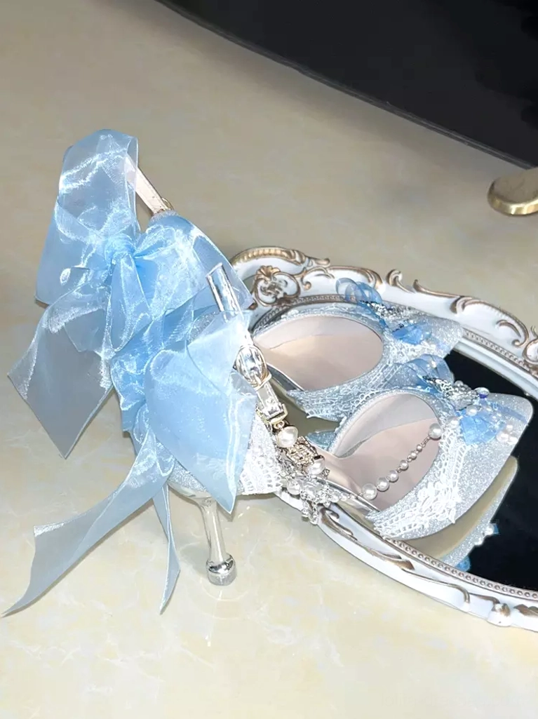 Pair of matching Lolita stiletto shoes with glitter finish, bows and pearl chain embellishments full view